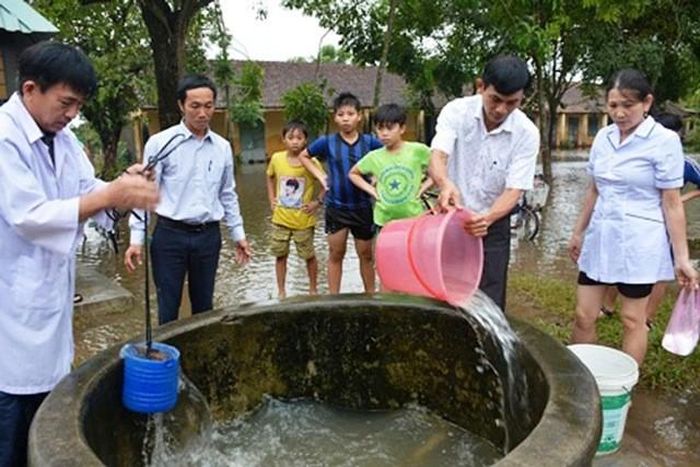 Cán bộ y tế hướng dẫn người dân vùng lũ vệ sinh nguồn nước sinh hoạt phòng ngừa dịch bệnh sau khi nước lũ rút