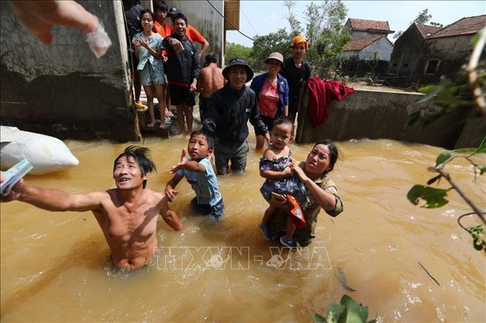 Người dân thôn Phú Thọ (xã An Thủy, huyện Lệ Thủy, tỉnh Quảng Bình) nhận tiền cứu trợ trong dòng nước lũ vẫn ngập sâu. Ảnh: Thành Đạt/TTXVN