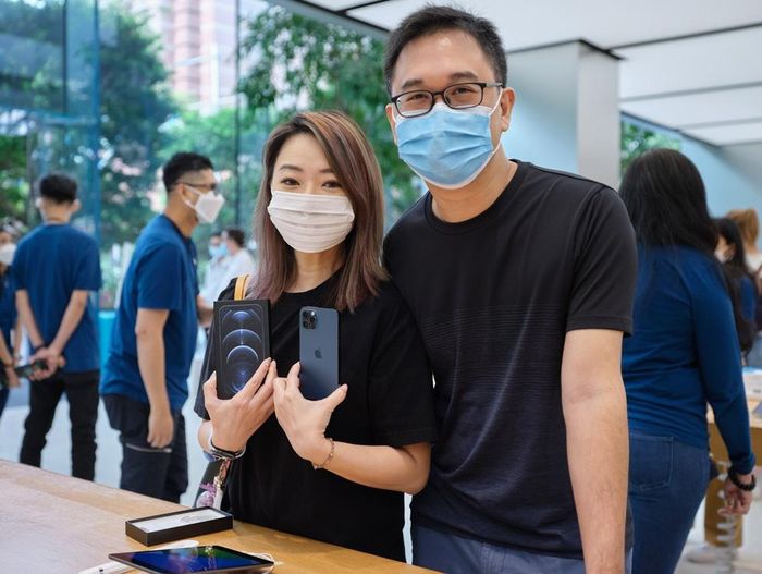  Người dùng trên tay iPhone 12 Pro tại Apple Store Orchard Road (Singapore) trong ngày mở bán. Khách hàng và nhân viên được yêu cầu đeo khẩu trang, giữ khoảng cách 1,5 m và kiểm tra thân nhiệt trước khi vào trong. Ảnh: Apple. 