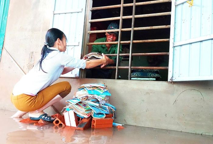 Một đôi vợ chồng ở rốn lũ Cẩm Thành (Hà Tĩnh) dọn dẹp sách vở của con sau lũ