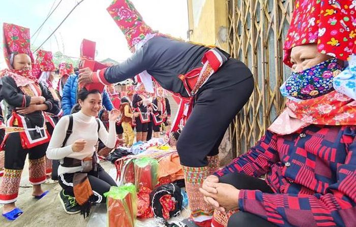Một du khách hứng khởi được người bán hàng cho đội thử chiếc mũ của dân tộc mình. Giá của chiếc mũ được người bán đưa ra là 1,1 triệu đồng