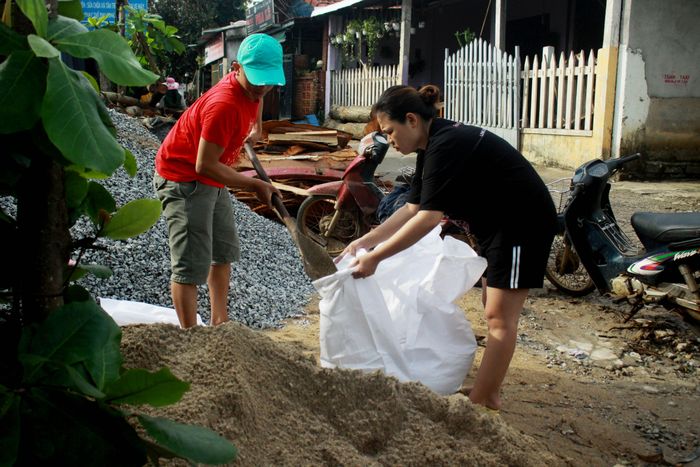 Thêm cát vào bao để chèn mái tôn tại xã Bình Hải, huyện Bình Sơn. Ảnh: NGUYỄN TRANG