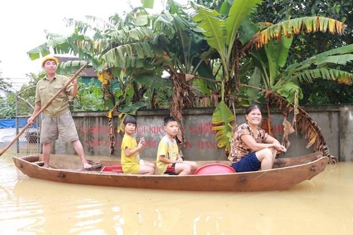 Nước dâng cao khắp mọi nẻo đường khiến người dân phải di chuyển bằng thuyền. (Ảnh: Bích Huệ/TTXVN)