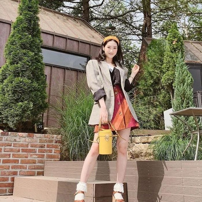 Bộ trang phục của MiuMiu gồm áo sơ mi trị giá 1.440 USD và chân váy 1.725 USD mà Joy từng mặc cũng "học hỏi" không ít từ Jiho. Nếu "gà" nhà SM tạo điểm nhấn vào đôi sandal đế bệt màu đỏ và mũ nơ lớn, thành viên Oh my girl lại mang đến hình ảnh xinh xắn cùng băng đô kèm áo vest kẻ. Ảnh: Koreaboo.