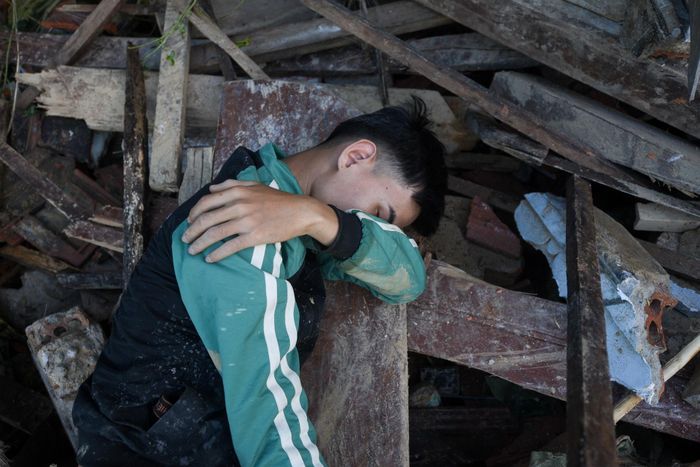  Quang nằm xuống đống đổ nát vì tuyệt vọng sau khi cùng người dân tìm kiếm người bố mất tích. 