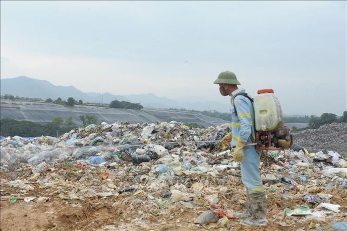 Công nhân Công ty TNHH MTV Môi trường Đô thị Hà Nội phun thuốc phòng trừ muỗi tại bãi rác Nam Sơn.