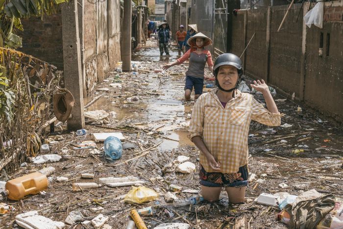Người dân di chuyển trên đường bị ngập rác do lũ