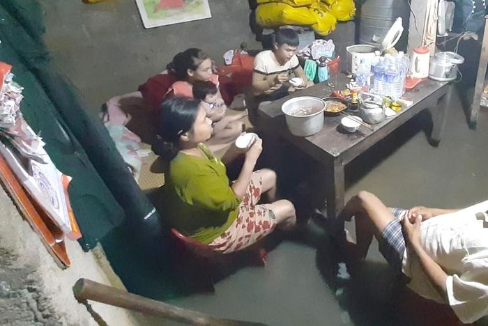 Bữa cơm gia đình trong căn nhà ngập nước ở vùng rốn lũ Quảng Điền (Thừa Thiên - Huế). Ảnh: VĂN THẮNG
