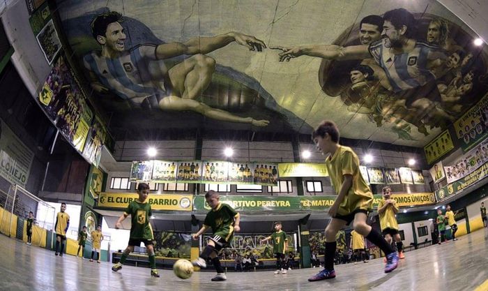 Trên trần nhà một sân futsal ở Buenos Aires (Argentina), bức họa "Sự tạo dựng Adam" được biến tấu dưới hình ảnh của Lionel Messi và Diego Maradona. Các cầu thủ nhí chơi bóng với ước mơ một ngày được khoác áo đội tuyển quốc gia.