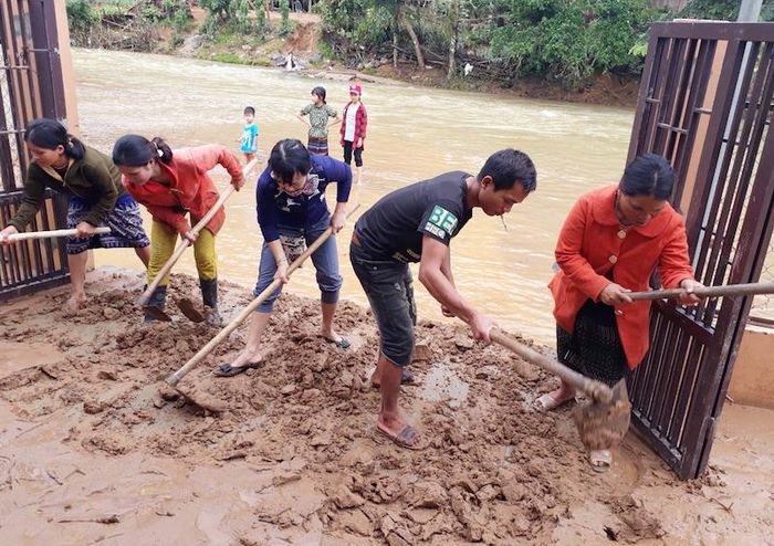 Cô giáo mầm non cùng dân bản dọn bùn đất do lũ mang vào ngập trường. 