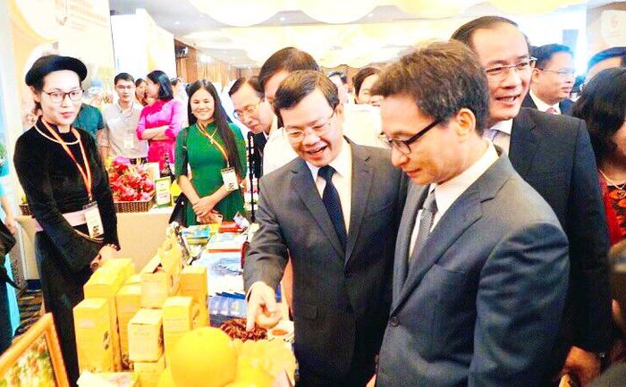 Chủ tịch UBND tỉnh Nguyễn Văn Sơn giới thiệu với Phó Thủ tướng Vũ Đức Đam sản phẩm trưng bày tại gian hàng của Tuyên Quang.