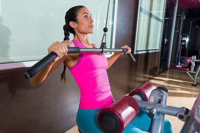  Lats: Động tác này tạo áp lực trực tiếp lên các cơ xung quanh lưng và giúp giảm đau cổ, vai, gáy. Cách thực hiện: Ngồi vào máy với thanh gắn với tạ. Sau đó, bạn nắm lấy thanh ngang sao cho khoảng cách giữa hai tay rộng hơn vai. Tiếp đến, bạn hóp bụng, ưỡn ngực rồi từ từ thở ra đồng thời kéo thanh tạ xuống đến khi chạm ngực. Động tác này cần được giữ vài giây, sau đó nâng thanh tạ trở về vị trí ban đầu và lặp lại 15 lần. Ảnh: Eatthis.