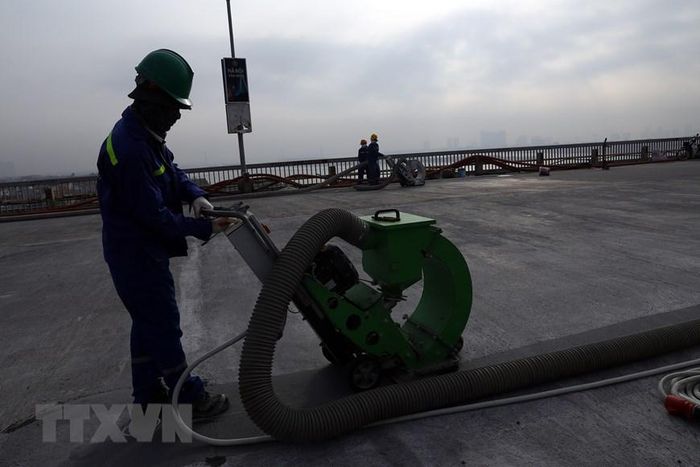 Từ nay đến cuối năm 2020, các đơn vị thi công sẽ tạo nhám, quét keo Epoxy dính bám và thi công lớp phủ mặt cầu. (Ảnh: Huy Hùng/TTXVN)