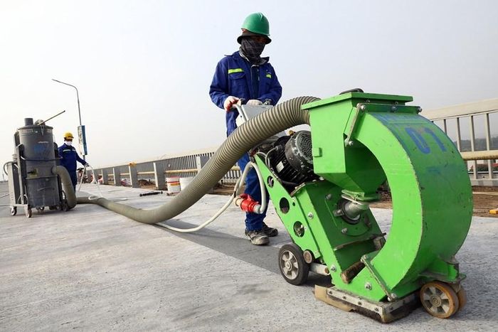 Thi công lớp tạo nhám, quét keo Epoxy dính bám. (Ảnh: Huy Hùng/TTXVN)