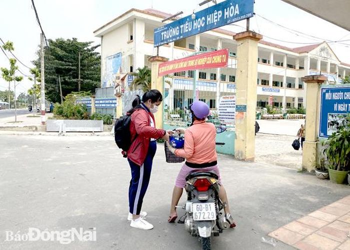 Học sinh Trường tiểu học Hiệp Hòa (TP.Biên Hòa) được cha mẹ đưa đến trường từ hơn 12 giờ trưa. Ảnh: C.Nghĩa