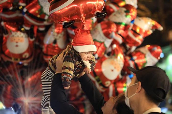Một bé trai được cha mẹ đưa đi chơi đêm Giáng sinh.