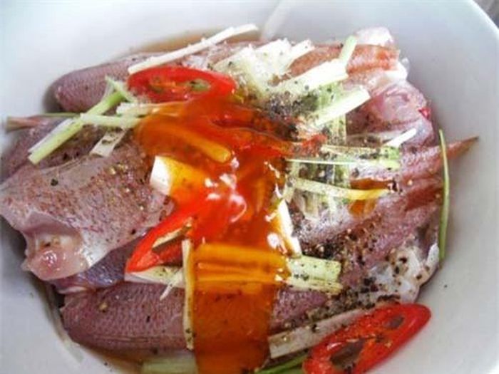 Lần lượt xếp kín cá kín nồi rồi thả thêm vài lát riềng lên trên.