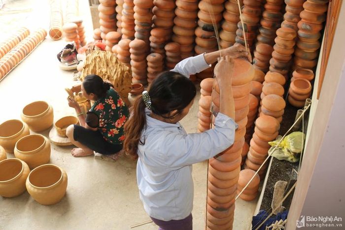 Những chiếc nồi đất mới ra lò, màu đỏ tươi được những người buôn nồi lựa chọn kỹ lưỡng. Chiếc nồi nào ưng ý, họ để riêng và sắp vào gióng. Gióng cột nồi là 4 thanh tre nhỏ bằng chiếc đũa, dài tầm 2m nối với nhau tạo thành hình chữ thập. Nồi cùng loại được xếp thành chồng cao và cột thành từng cây nồi khá chắc chắn. Ảnh: Huy Thư