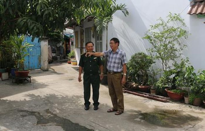 Cựu Chiến binh Lê Minh Phong (người mặc quân phục) đang bàn bạc cùng đồng đội để trồng thêm hoa và cây xanh trên con đường do anh tình nguyện hiến đất. Ảnh: Hồng Thái