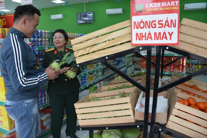 Thượng tá Nguyễn Thị Hường, Chủ tịch Công đoàn cơ sở Nhà máy Z129 giới thiệu khu vực bán nông sản sạch từ các mô hình tăng gia sản xuất của nhà máy. 