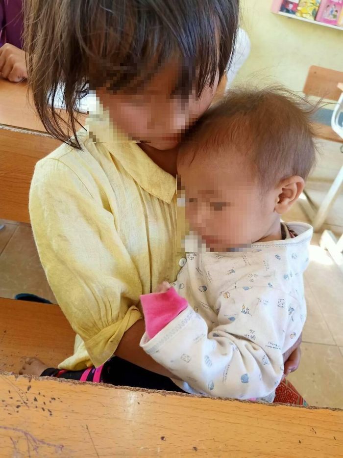  Được cô giáo pha bột đậu và cho ăn, em bé ngoan trong vòng tay chị Cở. 