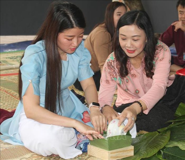 Khách tham quan trải nghiệm gói bánh chưng tại "Không gian chợ Tết xưa". Ảnh: Thùy Dung/TTXVN