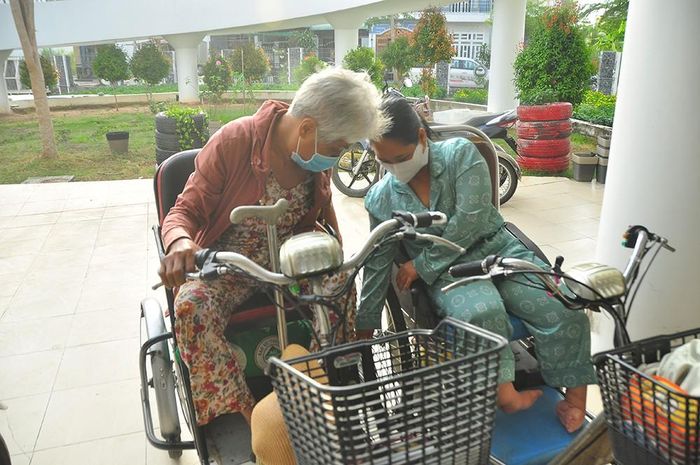 Chị Bé Đẹp (bên phải) giúp đỡ bà Kim Châu khóa bánh xe 