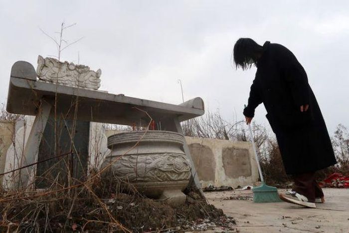  Deng quét dọn trước mộ phần của người thân ở Vũ Hán. Ảnh: Reuters. 