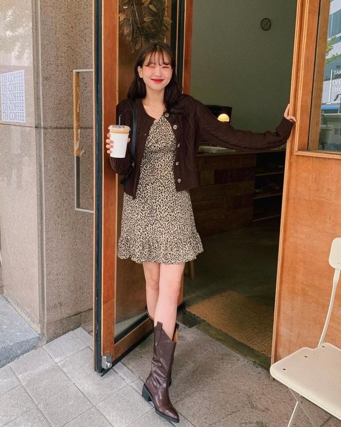Nếu trời chỉ se lạnh, bạn khoác ngoài váy liền chiếc áo cardigan là ổn. Outfit của quý cô này cũng giúp hack dáng vi diệu nhờ chọn váy ngắn, áo cardigan dáng lửng. Đôi boots cao cổ không ảnh hưởng đến khả năng tôn dáng của outfit; bên cạnh đó còn giúp set đồ trông thời thượng, "ăn chơi" hơn.