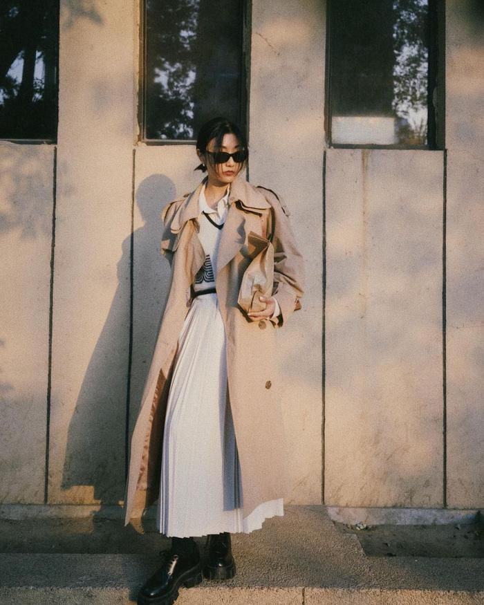Khoác ngoài váy sơ mi trắng một chiếc trench coat, đi giày boots đen và quý cô này đã có được set đồ cực kỳ sang trọng, chuẩn fashionista. Chiếc áo gilet bên trong không hề thừa thãi mà tạo điểm nhấn thú vị, sành điệu và trẻ trung cho tổng thể.