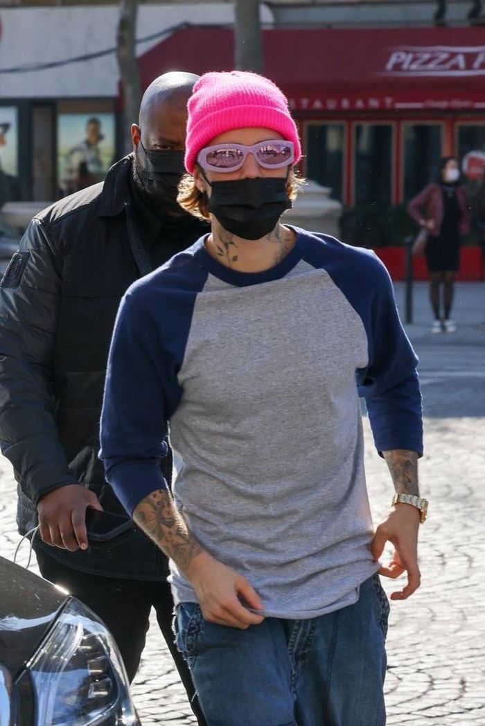 Đối với bộ đồ theo phong cách cá tính, Justin Bieber tạo điểm nhấn với mũ beanie màu hồng. Để hợp với mũ, nam ca sĩ phối cùng kính mắt dáng tròn, tông tím. Ảnh: Vogue.