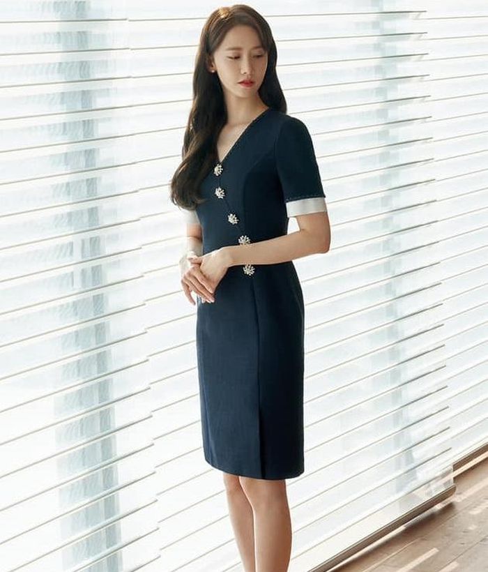 Lười lên đồ cầu kỳ đến công sở thì bạn hãy chọn diện mẫu váy liền đơn giản như của Yoona. Thiết kế dáng basic, váy ngắn trên đầu gối giúp tôn dáng tốt hơn. Ngoài ra váy còn có chi tiết hàng khuy đính đá dọc chéo theo thân váy tạo cảm giác trẻ trung và thành điểm nhấn cho tổng thể thu hút hơn.