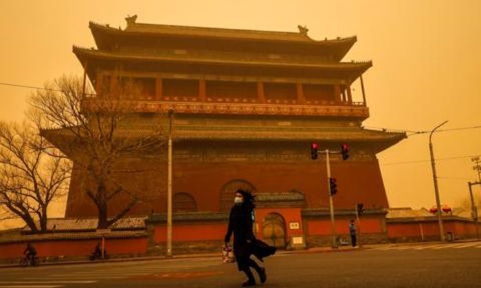 Một người phụ nữ di chuyển trong lúc bụi cát vây quanh - Ảnh: Reuters