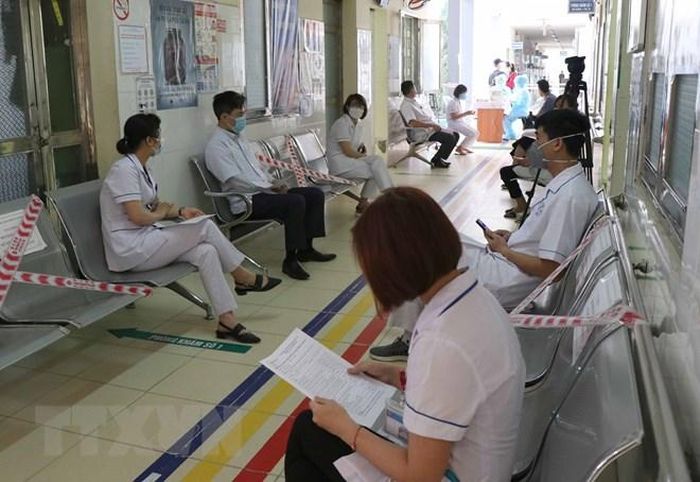 Sau quá trình khám, sàng lọc người chờ tiêm vaccine phòng COVID-19 được bố trí đảm bảo giãn cách ngoài hành lang. (Ảnh: Xuân Tiến/TTXVN)
