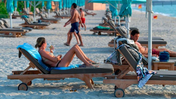 Che mặt là yêu cầu bắt buộc ở tất cả nơi công cộng ở Dubai. Những người tắm nắng hoặc ăn trong nhà hàng được miễn đeo khẩu trang. Ảnh: Giuseppe Cacace, Karim Sahib/AFP.