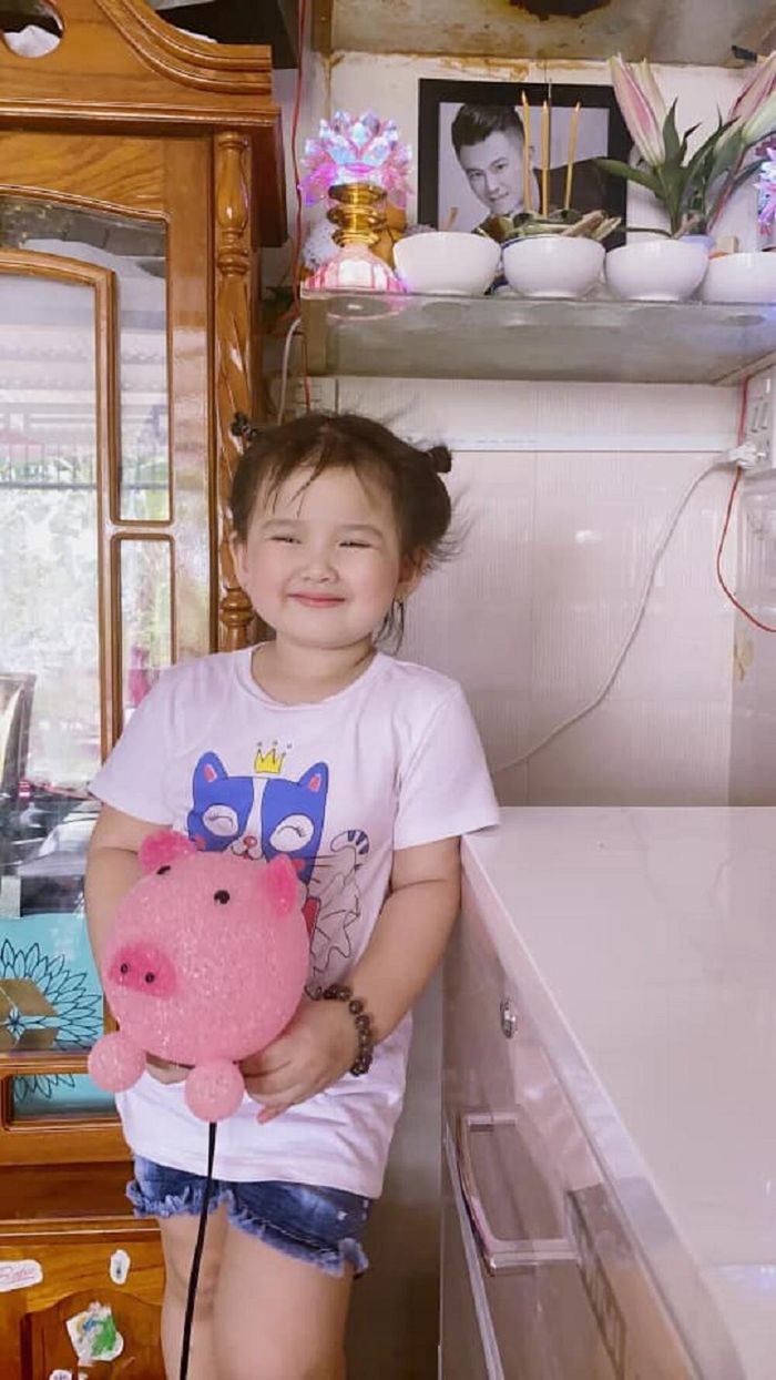 Bé Helen ôm đèn ngủ hình con heo trước bàn thờ ca sĩ Vân Quang Long.