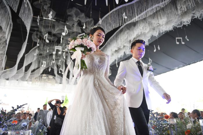  Phan Mạnh Quỳnh chăm chút, chăm sóc Khánh Vy trong suốt quá trình diễn ra hôn lễ. Anh nâng váy, nắm tay cô khi bước lên sân khấu. Quảng trường xứ Vạn Phần - nơi diễn ra hôn lễ được trang hoàng đẹp mắt với nhiều hoa tươi, ruy băng. Gia đình nam nhạc sĩ chuẩn bị 70 mâm cỗ để mời khách. Thực đơn gồm các món ăn truyền thống, mang hương vị quê nhà như gà luộc, ốc hương hấp, mực trứng hấp, xôi lạc dừa, cá năng chiên xù... 