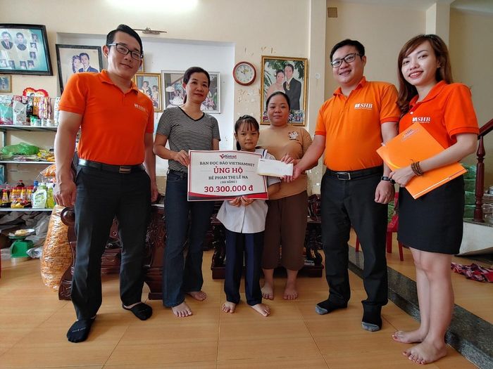 Đại diện báo VietNamNet và Ngân hàng Thương mại Cổ phần Sài Gòn – Hà Nội (SHB) trao tiền cho bé Lê Na.