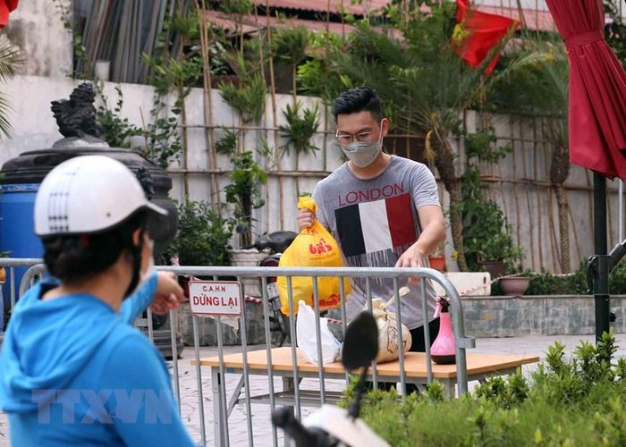 Người thân đưa đồ nhu yếu phẩm thiết yếu tiếp tế cho cư dân sống tại Tòa chung cư Viễn Đông Star (số 1 phố Giáp Nhị, quận Hoàng Mai, Hà Nội) bị phong tỏa. Ảnh: Phạm Kiên - TTXVN
