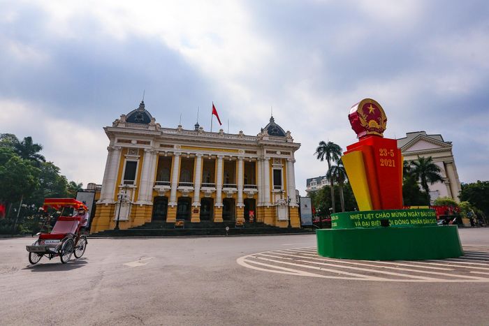Nhà hát Lớn lúc 9h thưa thớt xe cộ, vắng vẻ hơn so với thường ngày. Tròn 1 tuần nữa là tới ngày bầu cử đại biểu Quốc hội khóa XV và đại biểu HĐND các cấp nhiệm kỳ 2021 - 2026, vòng xuyến trung tâm quảng trường Cách mạng Tháng 8 đã được trang trí biểu ngữ tuyên truyền cổ động.