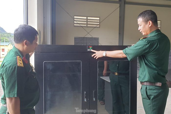 Thiếu tá Lê Anh Tuấn (bên phải) trao đổi với đồng đội về tính năng của tủ bảo quản khí tài quang học chuyên ngành biên phòng