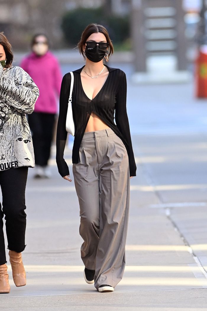 Xu hướng mặc áo sơ mi, áo cardigan thả hàng cúc dưới được nhiều sao Hollywood yêu thích, bao gồm Emily Ratajkowski. Lúc mang thai hay sau khi sinh con, cô nhiều lần lăng xê phong cách này. Nữ người mẫu diện áo cardigan trễ nải tôn đường cong. Chân dài phối kèm quần ống rộng cạp cao, giày sneakers và túi đeo vai giản đơn.