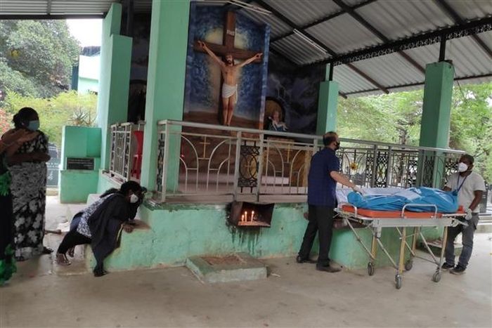 Một gia đình đau buồn đưa tiễn người thân qua đời vì COVID-19 khi phải giữ khoảng cách. (Ảnh: ST)