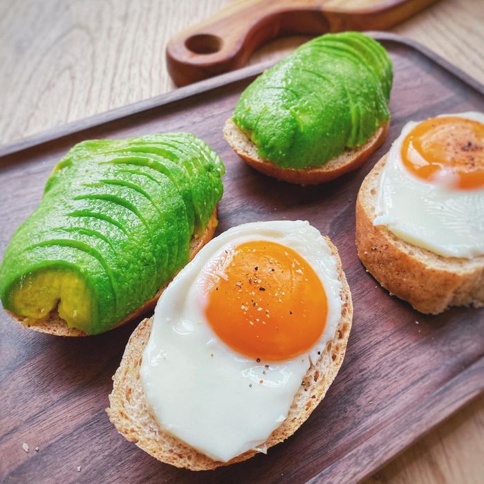 Đang trong mùa bơ, bạn có thể tận dụng loại trái cây bổ dưỡng này để chế biến bữa sáng. Bữa ăn nhanh gọn và dinh dưỡng này gồm có bơ thái lát, trứng lòng đào và bánh mì nguyên cám.