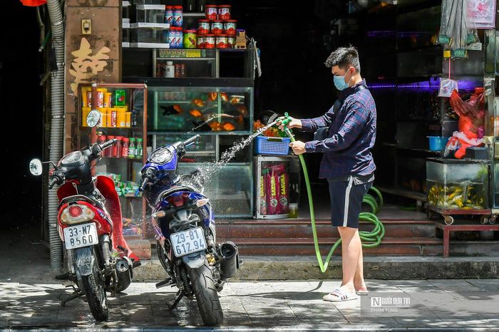 Dùng vòi nước xịt lên yên xe cho đỡ nóng, anh Nam (Hoàn Kiếm, Hà Nội) chia sẻ: "Trời tiết nắng nóng quá, để xe như này mà lên đi luôn thì không được, phải cho nước để giảm nhiệt đã".