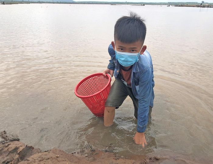 Em Lê Đức Hải (xã Ia Lâu, huyện Chư Prông) vô cùng thích thú khi được đi bắt hến cùng cha mẹ. Ảnh: Phương Dung