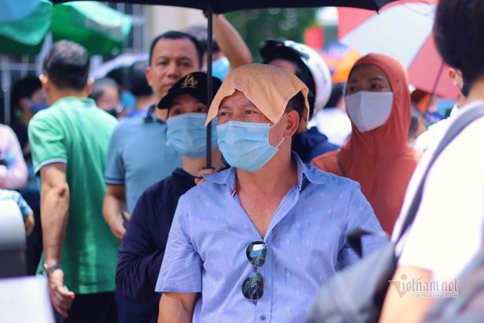 Vị phụ huynh "phủ" đầu bằng khăn lạnh để đợi con giữa cái nóng hầm hập.