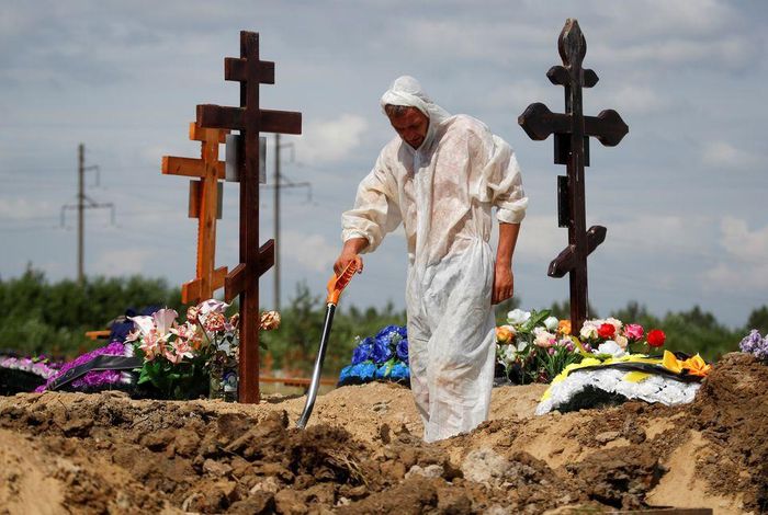 Một người đào mộ chôn bệnh nhân chết vì Covid-19 tại rìa thành phố Saint Petersburg, Nga vào ngày 25/6. Ảnh: Reuters.