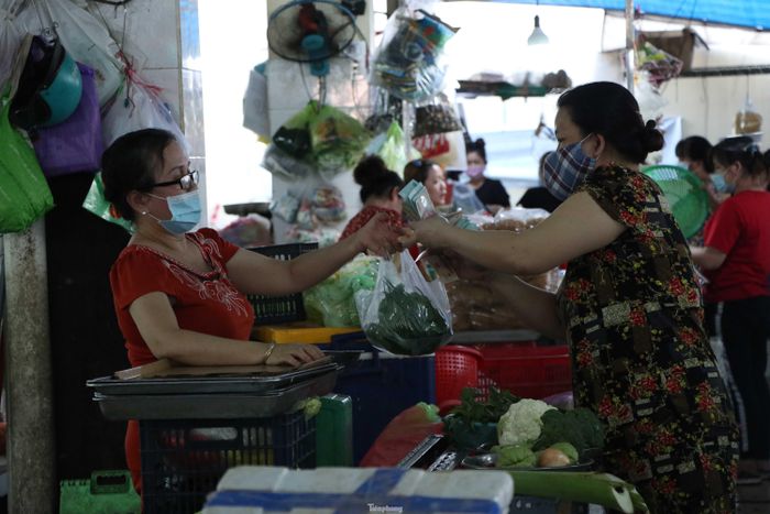 Sau khi xuất trình thẻ đi chợ và được nhân viên quản lý lưu số thẻ trong sổ, người dân sẽ được vào chợ để mua sắm nhu yếu phẩm, thực phẩm.
