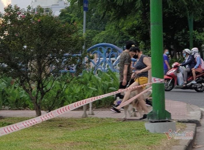 Một cô gái đạp lên dây căng phong tỏa công viên để dẫn thú cưng tản bộ dọc kênh Nhiêu Lộc- Thị Nghè